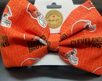 May include: Orange and brown bow tie with a repeating pattern of the Cleveland Browns logo and the words "Cleveland Browns".