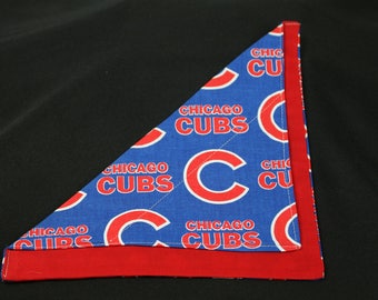 May include: A red and blue triangular bandana with the text "CHICAGO CUBS" repeated on a blue background. The bandana is folded in half and the red side is facing out.