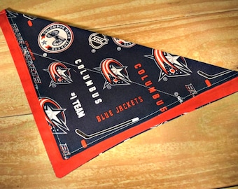 May include: A blue and red fabric triangle with the words "Columbus Blue Jackets" and the team logo. The fabric is patterned with the team logo and the words "Columbus Blue Jackets".