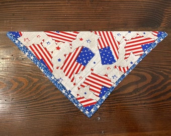 May include: A white bandana with a blue and red American flag pattern. The bandana has a blue and white trim with white stars.