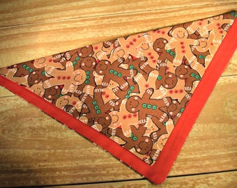 May include: A red and brown triangular fabric with a gingerbread man pattern. The fabric has a red border.