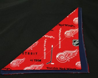 May include: Red bandana featuring the Detroit Red Wings logo and text. The red fabric has white logos and text, including "Detroit Red Wings" and "#1 TEAM". A navy blue border frames the bandana.