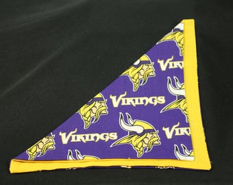 May include: Purple and yellow fabric with a repeated pattern of Viking helmets and the word "Vikings".
