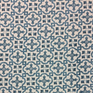 May include: A white fabric with a repeating blue pattern of stylised flowers and geometric shapes.