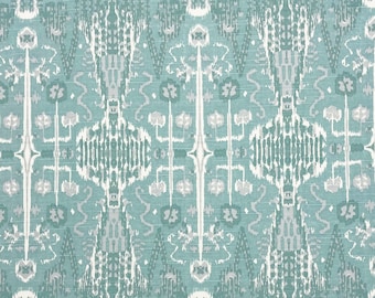 Puede incluir: Una tela azul turquesa con un patrón ikat blanco y gris. El patrón es simétrico y presenta un diseño repetitivo de diamantes, espirales y flores.
