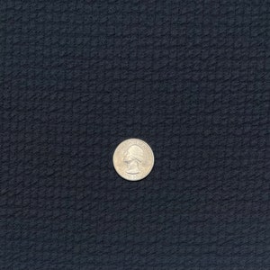 May include: A silver US quarter coin on a dark blue textured surface.