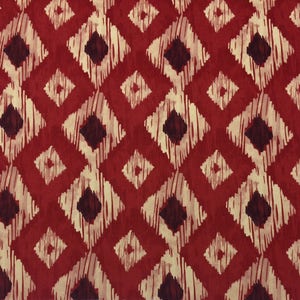May include: Red fabric with a repeating pattern of white and brown diamond shapes. The fabric has a textured, woven look.