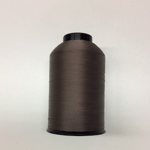 May include: A spool of brown thread for sewing or embroidery.