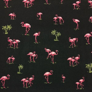 May include: A black fabric with a repeating pattern of pink flamingos and green palm trees.