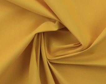 May include: Close-up of a folded piece of golden yellow fabric. The fabric has a subtle texture and is draped in soft folds, creating shadows and highlights. The color is a rich, warm tone, suggesting a natural fiber material.