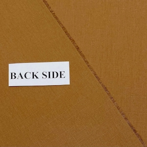 May include: Close-up of a piece of tan fabric with a diagonal seam. A white rectangle with the words "BACK SIDE" is in the centre of the image. The fabric has a textured appearance.