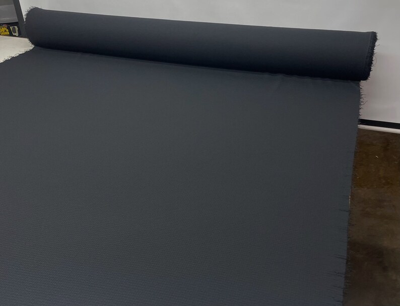 May include: A roll of dark gray fabric with a textured surface.