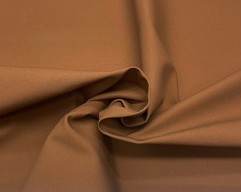 May include: Close-up of a swatch of tan fabric. The material is tightly woven with a subtle sheen. The folds and curves create shadows and highlights, adding depth and texture. The overall appearance is smooth and uniform. The fabric is a warm, neutral tone.