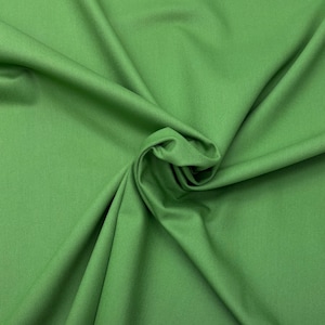 May include: A close-up shot of a vibrant green fabric with a subtle texture. The fabric is draped and folded, creating shadows and depth. The color is a bright, lively green, reminiscent of fresh spring foliage.