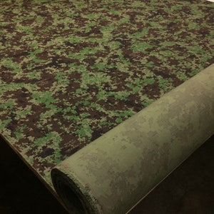 May include: A roll of green and brown camouflage fabric. The fabric is rolled up and the end of the roll is visible.