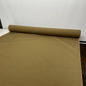 May include: A roll of brown fabric. The fabric is rolled up and the end of the roll is visible.