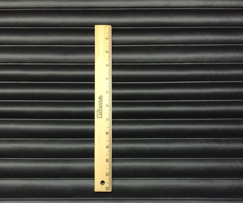 May include: Black quilted fabric with a ruler measuring 12 inches. The fabric has a horizontal ribbed pattern.