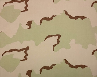 May include: A camouflage fabric pattern with brown, beige, and green colors. The pattern is made up of irregular shapes and lines.