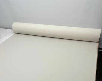 May include: A roll of white canvas fabric, partially unrolled on a white surface.