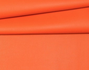 Puede incluir: Primer plano de un trozo de tela naranja brillante doblado. La tela tiene una superficie lisa y ligeramente texturizada.