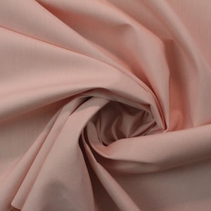 May include: A close-up of a soft, pale pink fabric with a smooth texture. The fabric is folded and draped, creating a gentle, flowing effect.