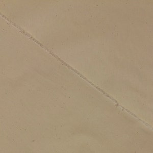 May include: A close-up of a beige surface with a diagonal seam running across it.