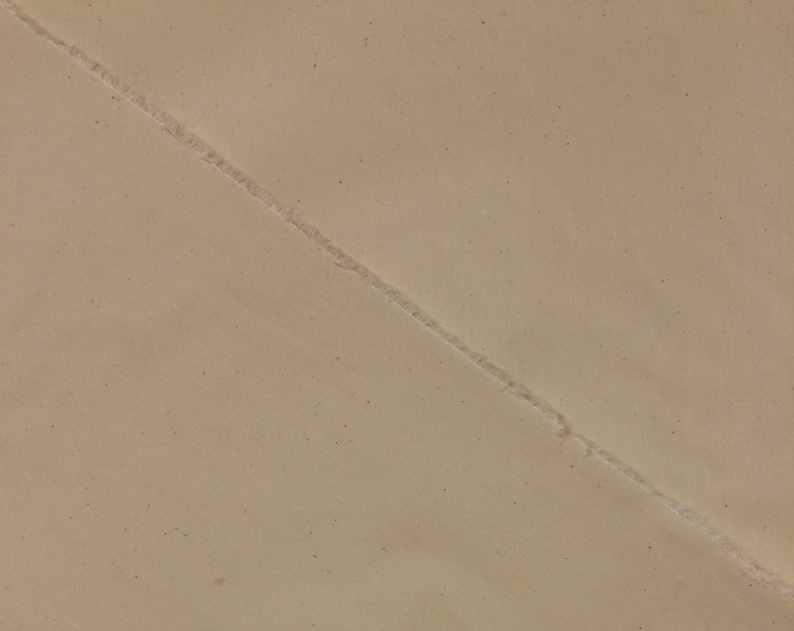 May include: A close-up of a beige surface with a diagonal seam running across it.