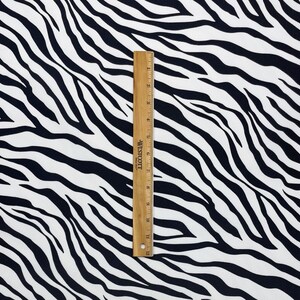 以下が含まれることがあります： 白黒のシマウマ柄の生地。生地は、30.5cmを測る定規の隣に示されています。