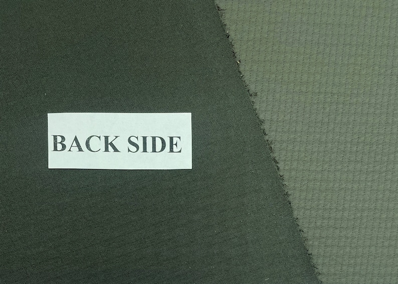 May include: Close-up of two fabric swatches in shades of green. The left swatch is a solid, darker green, while the right swatch is a lighter green with a textured, grid-like pattern. A white label with the text "BACK SIDE" is visible.