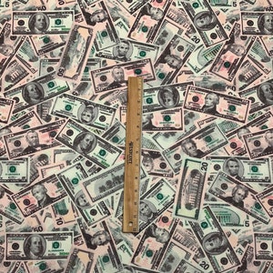 Pode incluir: Um close-up de um tecido com um padr&atilde;o de notas de d&oacute;lar americano. O tecido &eacute; branco com uma variedade de denomina&ccedil;&otilde;es de notas, incluindo $1, $5, $10, $20 e $50.