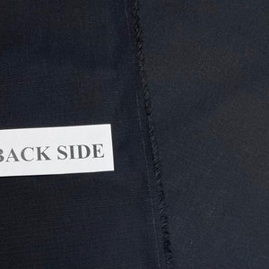 May include: A close-up of a black fabric with a label that says "BACK SIDE".