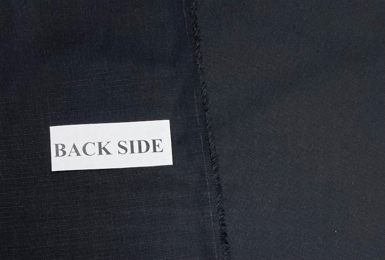 May include: A close-up of a black fabric with a label that says "BACK SIDE".