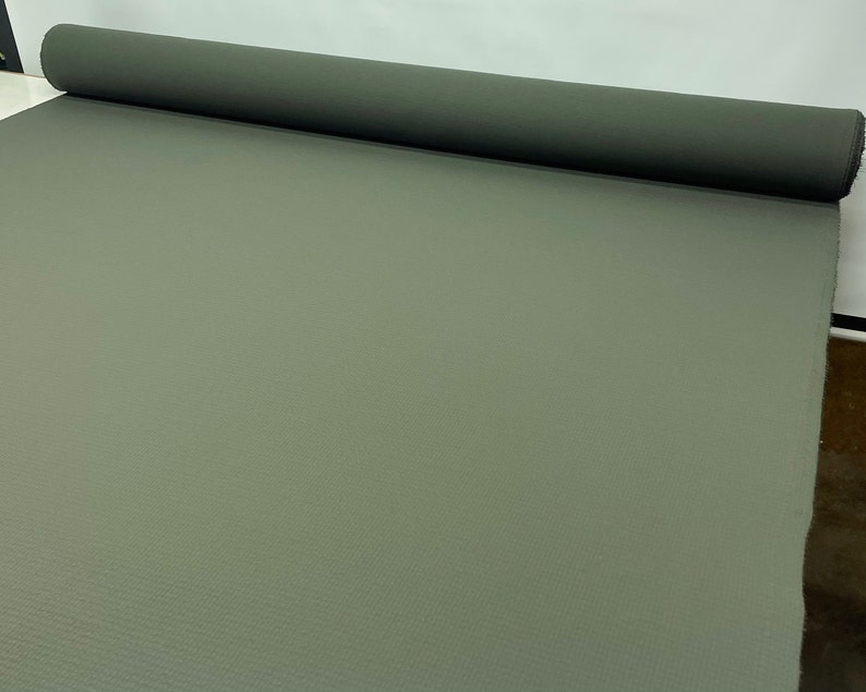 May include: A roll of olive green fabric, unrolled on a white surface. The fabric has a subtle texture and is suitable for various crafting and sewing projects. The roll is positioned horizontally, showcasing the material's width and color.
