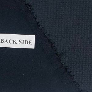 May include: Close-up of two pieces of dark blue fabric. One side has a smooth texture, while the other side has a textured pattern. The label reads "BACK SIDE".