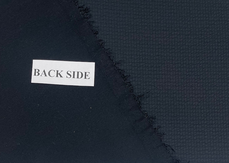 May include: Close-up of two pieces of dark blue fabric. One side has a smooth texture, while the other side has a textured pattern. The label reads "BACK SIDE".