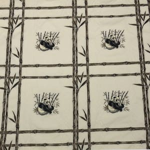 May include: White fabric with a repeating pattern of black and white pandas sitting in bamboo. The pandas are surrounded by brown bamboo stalks.