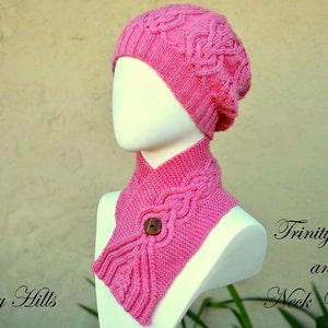 May include: A pink knitted hat and matching neck warmer with a cable knit pattern. The hat is a beanie style and the neck warmer has a button closure.
