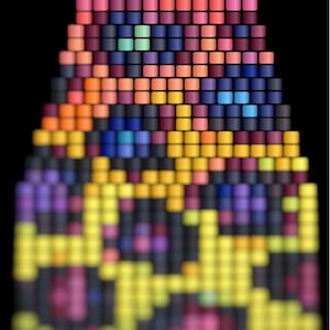 May include: A colorful, abstract design composed of small, square blocks. The pattern transitions from pinks and purples at the top, through oranges, yellows, and blues, to a green and black pattern at the bottom. The background is black.