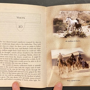 Pu&ograve; includere: Un libro con una copertina marrone e un'immagine di un cavallo bianco e un puledro nero sulla copertina. Il libro &egrave; aperto a una pagina con il titolo "Voices" e il numero 10. La pagina contiene anche del testo su un viaggio nel deserto e un'immagine di un convoglio di cammelli.