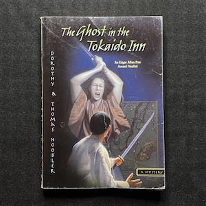 May include: A paperback book titled "The Ghost in the Tokaido Inn" by Dorothy & Thomas Hoobler. The cover art depicts a dramatic scene with a woman holding a sword, and a man in a kimono. The book is labeled as an Edgar Allan Poe Award Finalist.