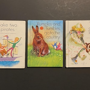 Może przedstawiać: Trzy książki dla dzieci z kolorowymi ilustracjami. Pierwsza książka nosi tytuł "Take Two Pirates" i przedstawia dwóch piratów na statku. Druga książka nosi tytuł "Rumples and Tumbles Go to the Country" i przedstawia brązowego królika. Trzecia książka nosi tytuł "Top and Toby" i przedstawia dziewczynkę i psa.