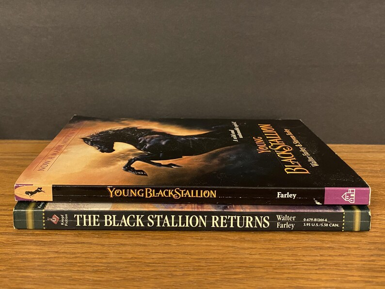 Pu&ograve; includere: Due libri tascabili impilati uno sopra l'altro. Il libro in alto &egrave; "Young Black Stallion" di Walter Farley. Il libro in basso &egrave; "The Black Stallion Returns" di Walter Farley.