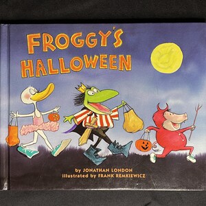 May include: A book cover with the title "Froggy's Halloween" in yellow letters. The cover features a frog dressed as a vampire, a duck dressed as a ballerina, and a pig dressed as a devil. The book is illustrated by Frank Remkiewicz.