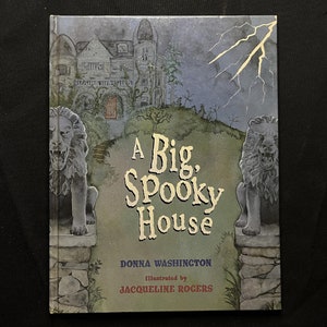 May include: A book cover featuring a spooky house illustration. The title is "A Big, Spooky House" by Donna Washington, illustrated by Jacqueline Rogers. The cover depicts a large, dark house with a lightning bolt in the sky and two stone lion statues.