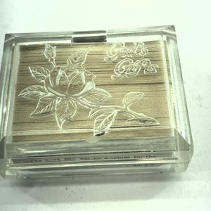 Puede incluir: Una taza de cerámica blanca con un asa negra y el texto "But First, Coffee" en negro, con una fuente de estilo manuscrito. La taza está sobre una superficie blanca.