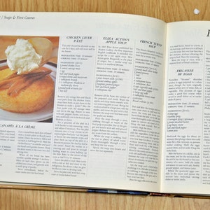 May include: Open cookbook with a recipe for Clam Pie, a traditional New England dish. The page features a close-up of the recipe with the ingredients listed, including clams, butter, flour, and milk.