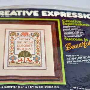 Puede incluir: Un kit de punto de cruz con un sampler de arte popular con el alfabeto en un dise&ntilde;o colorido. El kit incluye tela de 35,6 cm x 45,7 cm, hilo de bordar, una aguja e instrucciones f&aacute;ciles de seguir. El kit se titula "7935 Folk Art Sampler (14" x 18") Cross Stitch Kit".