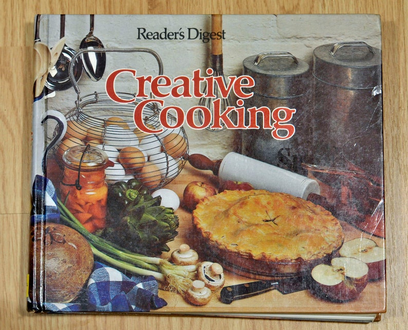 May include: A vintage cookbook titled "Reader's Digest Creative Cooking" with a colourful cover featuring a pie, eggs, vegetables, and a rolling pin.