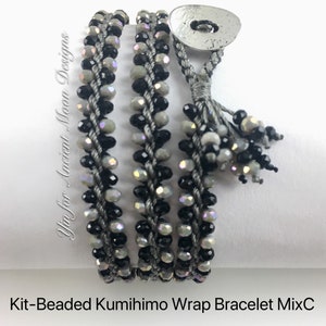 May include: A beaded Kumihimo wrap bracelet in shades of gray, black, and iridescent beads. The bracelet wraps around the wrist multiple times and fastens with a button closure. The text "Yin for Ancient Moon Designs" and "Kit-Beaded Kumihimo Wrap Bracelet MixC" are visible.