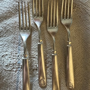 Peut inclure: Quatre fourchettes en argent avec des manches ornés. Chaque manche est décoré d'un motif de coquille.